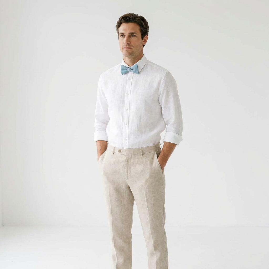 Man styling a Hemmitie dusty blue linen bow tie with a white rolled-sleeve shirt and beige pants.