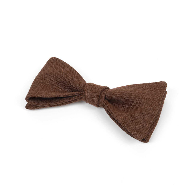 Side view close-up of a Hemmitie rustic brown linen bow tie showing the rich fabric weave and earthy texture.
