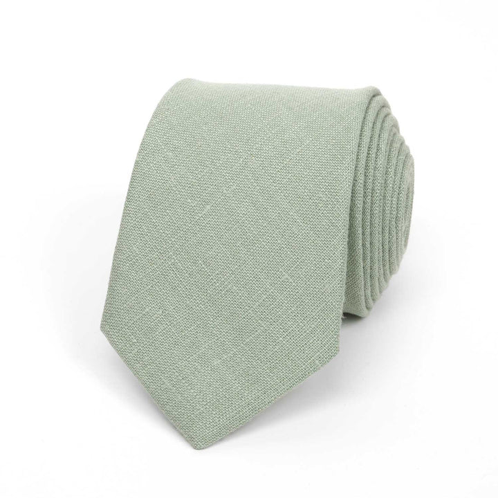 Front view of a light sage green necktie made from textured linen fabric, isolated on a white background.